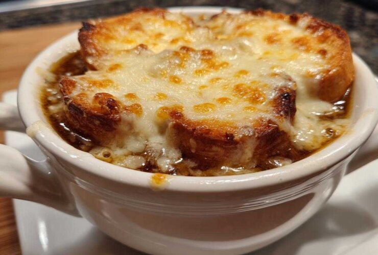 Close-up of a bowl of rich french onion soup topped with toasted bread and bubbly, melted Gruyère cheese.