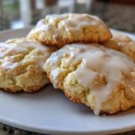 Close-up of four delicious earl grey cookies topped with a thick white glaze, resting on a white plate.