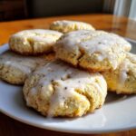Close-up of several soft, glazed earl grey cookies stacked on a white plate, showing visible tea flecks.