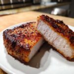 Close-up of two halves of juicy air fryer pork chops showing a perfectly cooked interior and seasoned crust.