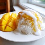 A serving of mango sticky rice featuring diced fresh mango and sticky rice topped with sweet coconut cream.
