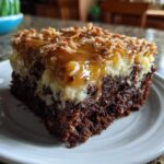 Close-up of a moist slice of german chocolate poke cake showing rich chocolate base and coconut-pecan topping.