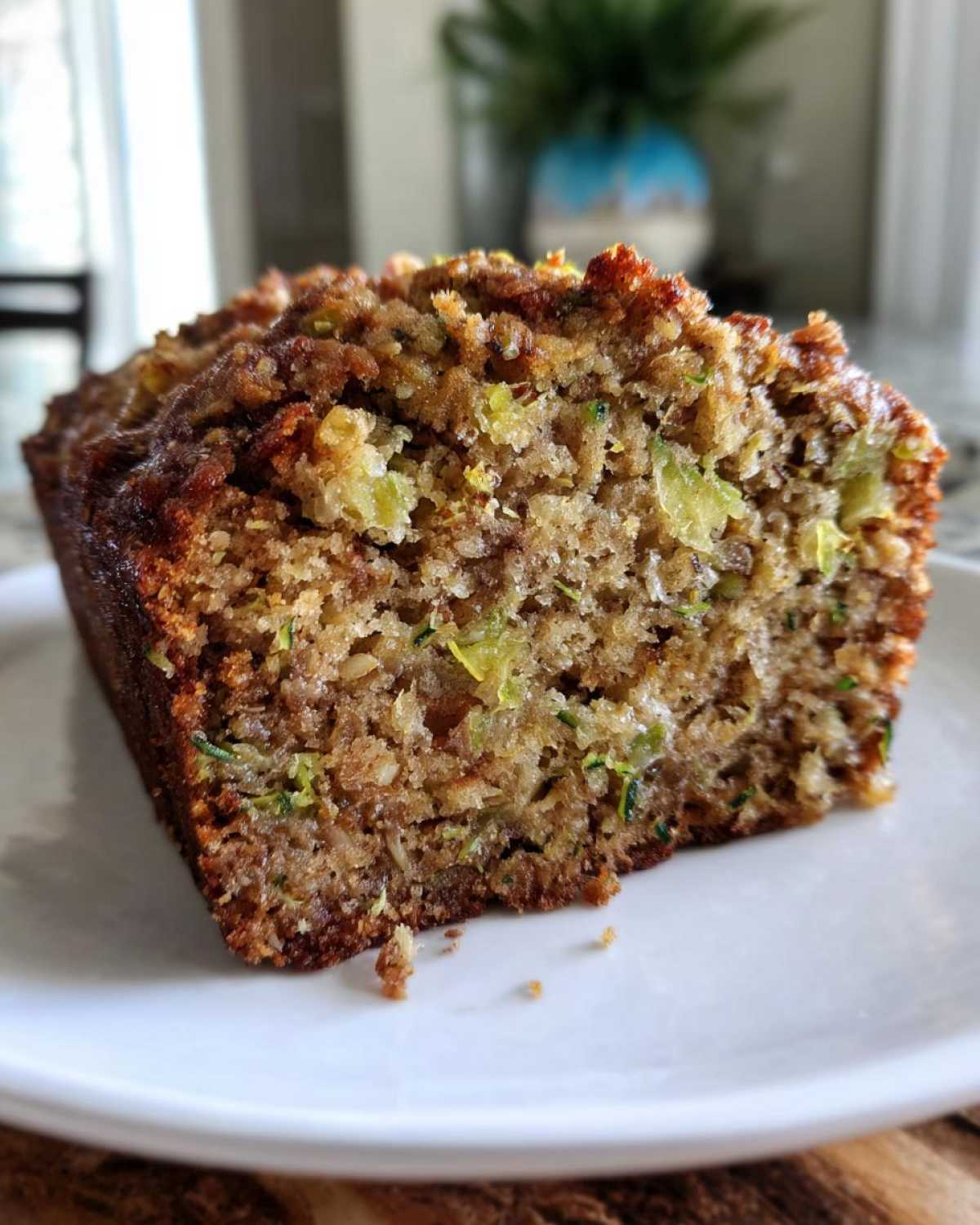 Close-up of a moist slice of zucchini banana bread showing shredded zucchini and a crunchy brown topping.