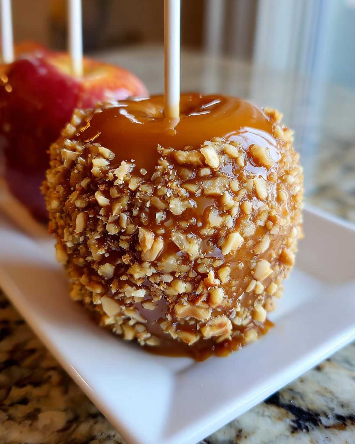 Close-up of a delicious caramel apple coated in chopped nuts, ready to eat.