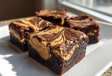 Close-up of four rich, fudgy peanut butter swirl brownies stacked on a white plate.