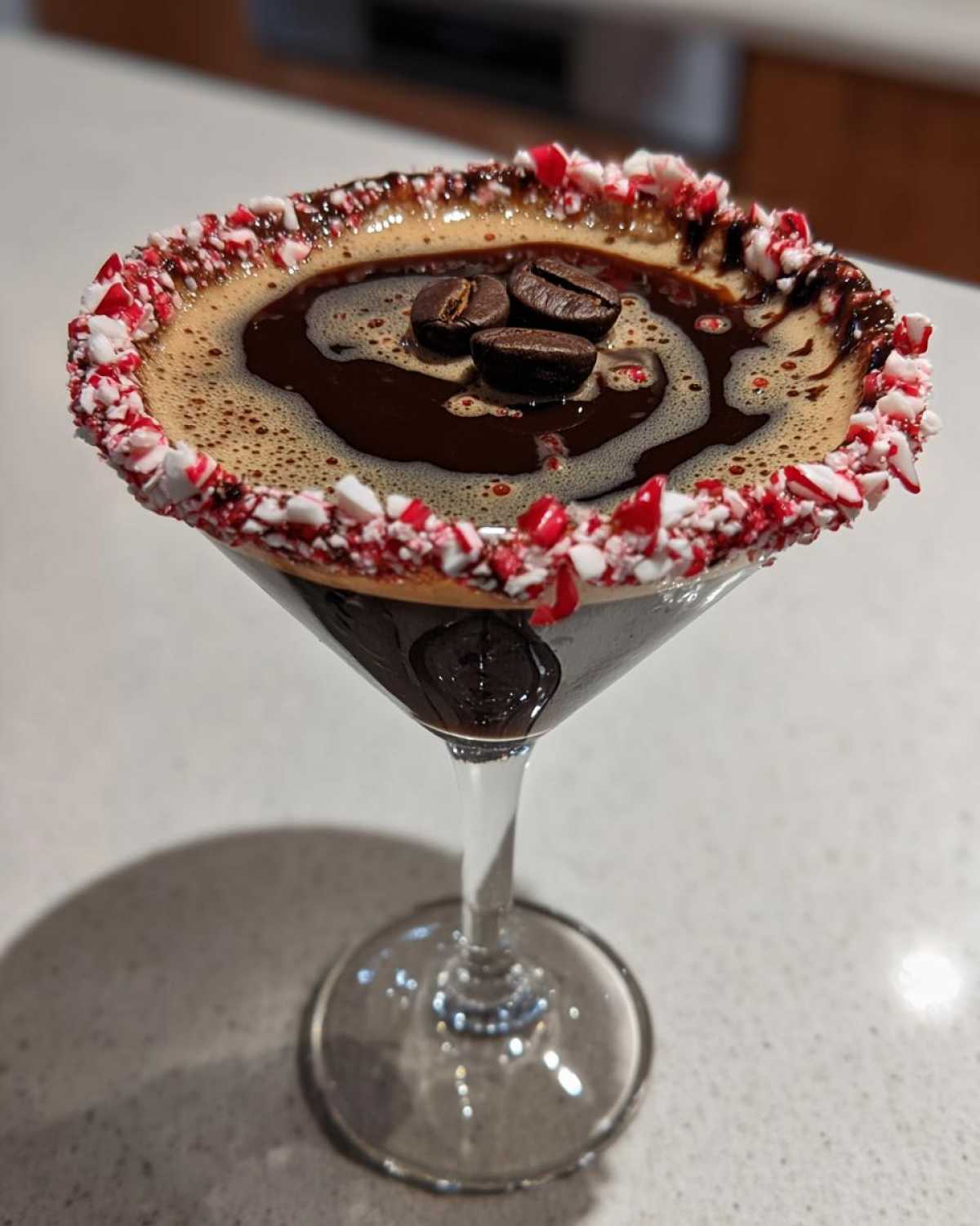A festive peppermint espresso martini garnished with coffee beans and a crushed candy cane rim.