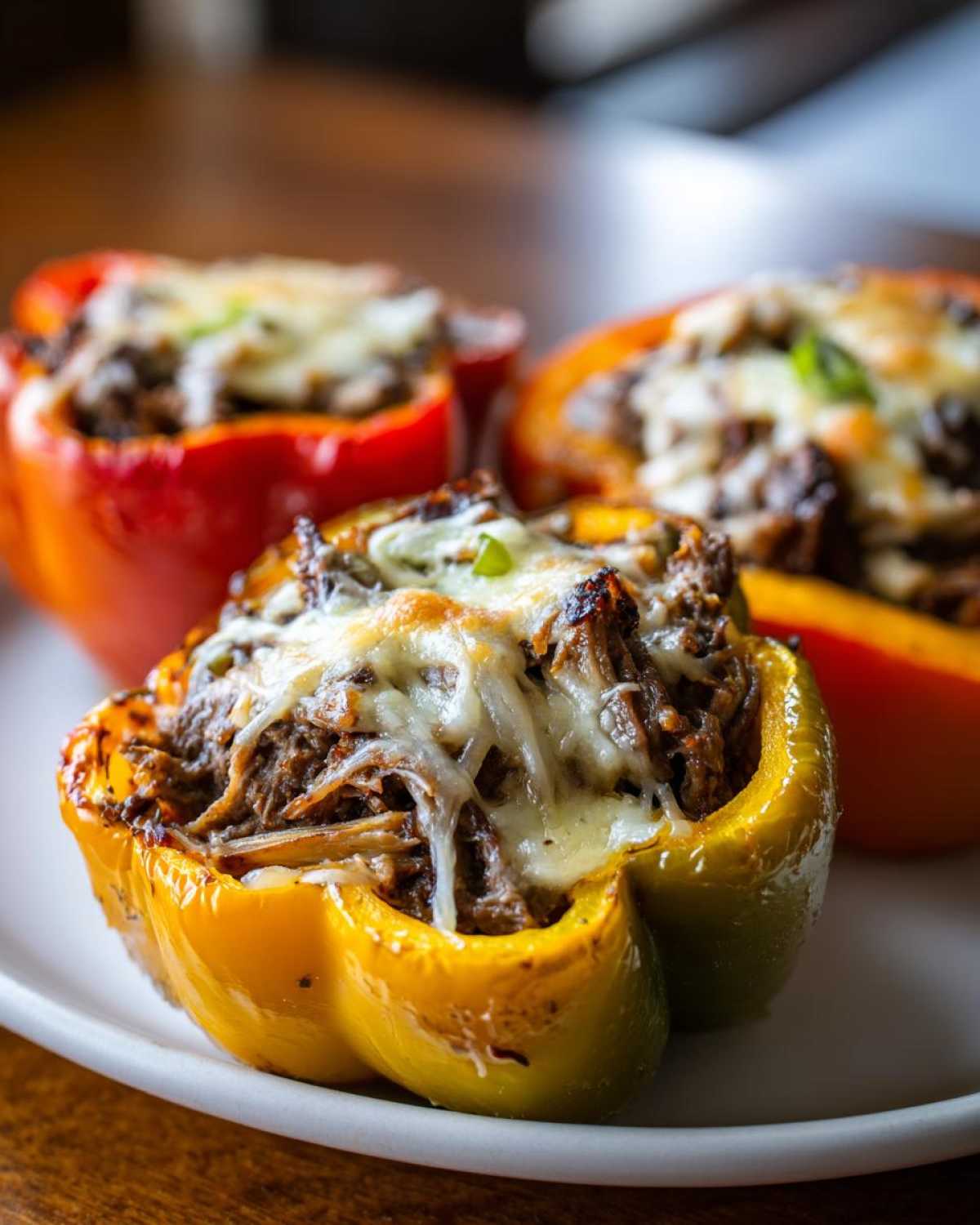 Close-up of baked philly cheesesteak stuffed peppers topped with melted white cheese.