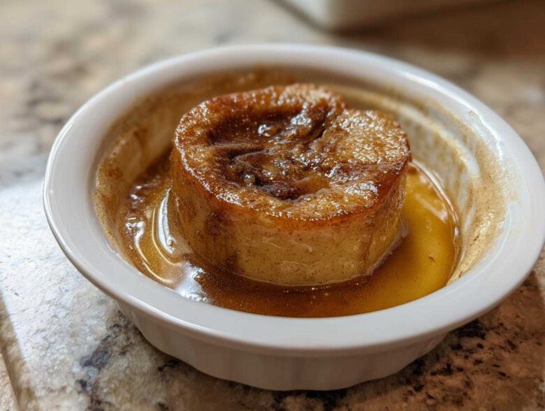 A single serving of a baked apple, caramelized and sitting in sweet brown syrup in a white ramekin.