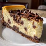 A perfect slice of chocolate chip cheesecake featuring a creamy filling swirled with chocolate chunks and topped with more chips.