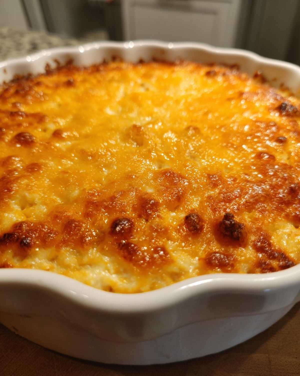 Close-up of hot, bubbly Texas Trash Dip baked in a white ceramic dish with a perfectly melted and browned cheese topping.