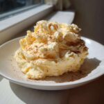 A dollop of fluffy, whipped honey butter recipe sprinkled lightly with cinnamon on a white plate.