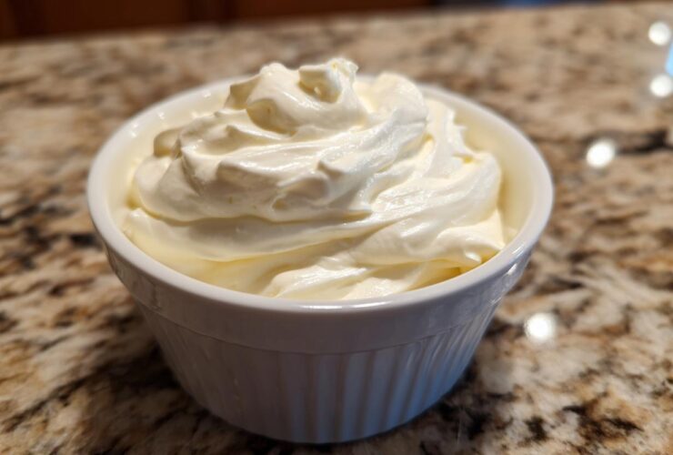 A close-up of creamy, whipped horseradish sauce mounded high in a small white bowl on a granite countertop.