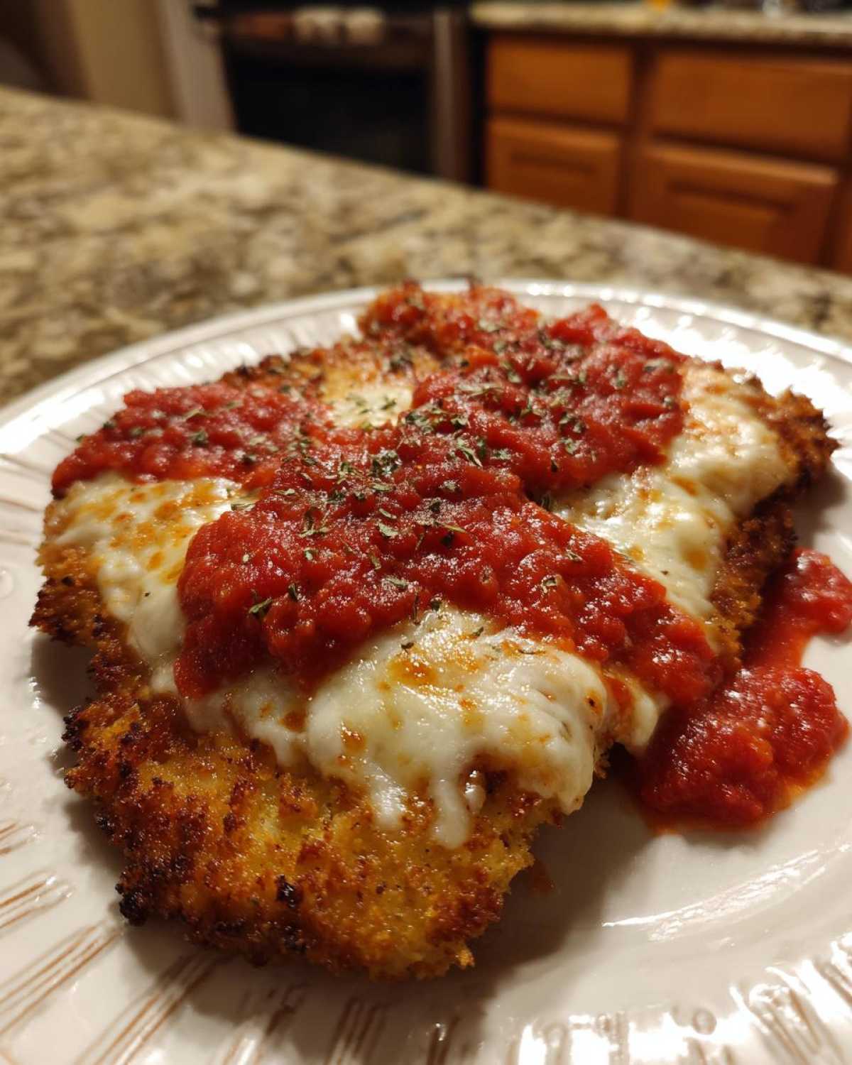 Close-up of golden, crispy Air Fryer Chicken Parmesan topped with melted mozzarella and marinara sauce.