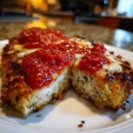 Close-up of Air Fryer Chicken Parmesan cut in half, showing crispy breading, melted cheese, and marinara sauce.