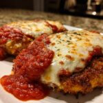 Two pieces of crispy Air Fryer Chicken Parmesan topped with melted mozzarella cheese and marinara sauce.