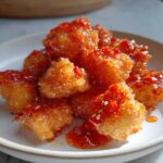 Golden brown cubes of Air Fryer Crispy Tofu generously drizzled with a shiny sweet chili glaze and sesame seeds.