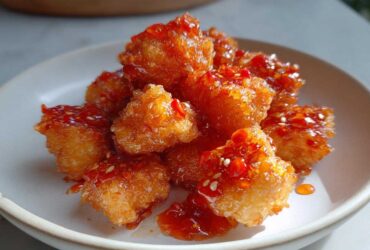 Golden brown cubes of Air Fryer Crispy Tofu generously drizzled with a shiny sweet chili glaze and sesame seeds.