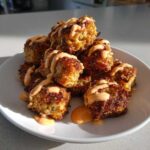 A pile of crispy Air Fryer Salmon Bites drizzled generously with orange Bang Bang Sauce on a white plate.