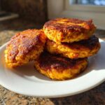 Four perfectly cooked Air Fryer Salmon Patties stacked on a white plate, showing a crispy, golden-brown exterior.