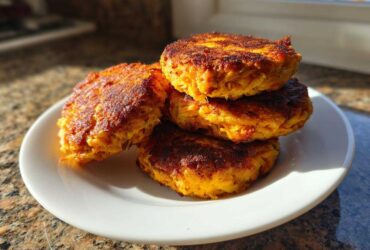 Four perfectly cooked Air Fryer Salmon Patties stacked on a white plate, showing a crispy, golden-brown exterior.