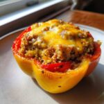 A close-up of a yellow Air Fryer Stuffed Bell Peppers half, topped with melted cheddar cheese and quinoa filling.