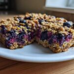 Two moist Blueberry Baked Oatmeal Squares cut in half, showing the rich, purple blueberry filling and oat topping.