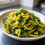 A close-up of vibrant green Cabbage Stir Fry with Garlic Ginger Sauce served on a white plate.