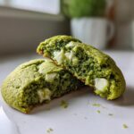 Close-up of Chewy Matcha White Chocolate Cookies broken in half, showing the moist green interior and melted white chocolate chips.
