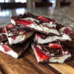 A stack of thick, layered Chocolate Covered Strawberry Bark pieces featuring dark chocolate, white filling, and sliced strawberries.