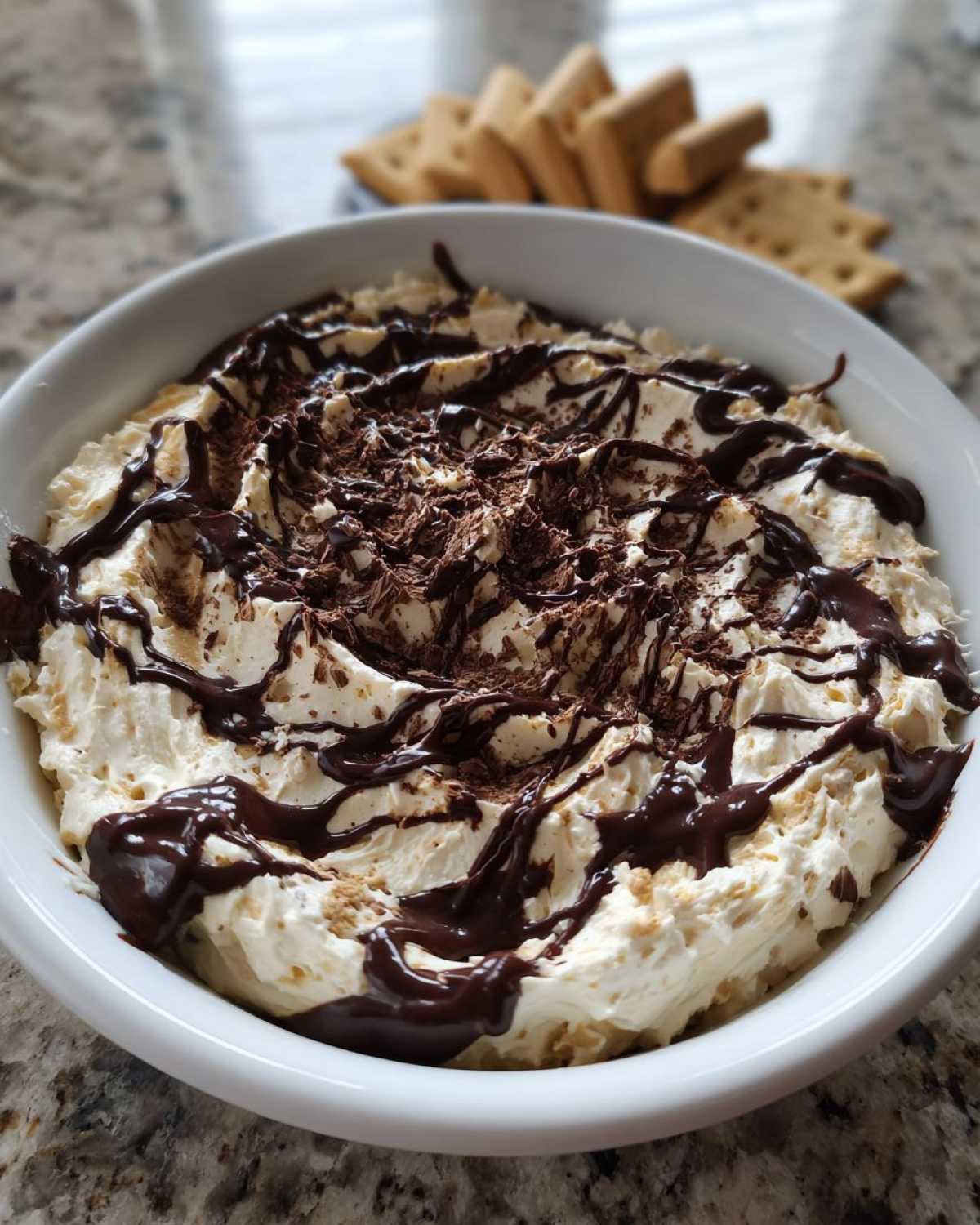 A bowl of creamy Chocolate Peanut Butter Cheesecake Dip topped with chocolate drizzle and shavings.