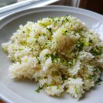 A close-up of fluffy white rice seasoned with chopped cilantro and bright green lime zest, perfect Cilantro Lime Rice.