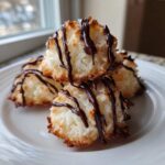 Close-up of chewy Coconut Macaroons with Dark Chocolate Drizzle stacked on a white plate.