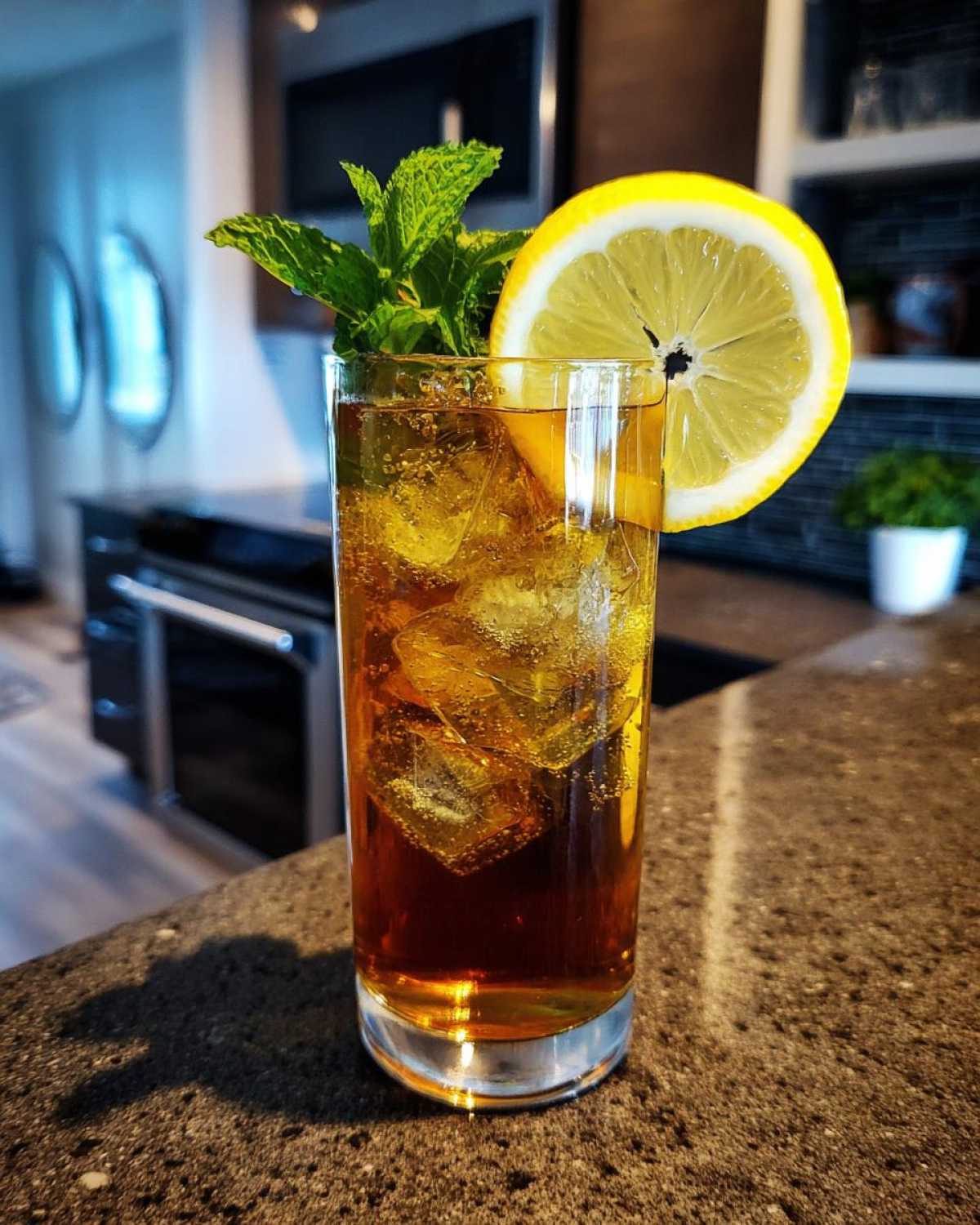 A tall glass filled with ice and dark Cold Brew Lemonade, garnished with a lemon wheel and fresh mint.