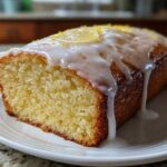 A moist slice of Copycat Starbucks Iced Lemon Loaf, topped with thick white glaze and lemon zest.