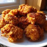 A close-up of golden brown, crispy air fryer cauliflower wings piled high on a white plate, perfectly cooked.