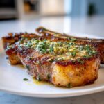 Close-up of juicy, crispy air fryer pork chops topped with melted garlic butter and fresh parsley.