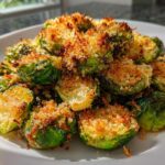 A plate of perfectly roasted Crispy Parmesan Brussels Sprouts with a golden, crunchy topping.