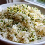 Close-up of fluffy Cilantro Lime Rice topped with chopped herbs and lemon zest in a white bowl.