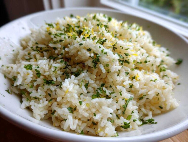 Close-up of fluffy Cilantro Lime Rice topped with chopped herbs and lemon zest in a white bowl.