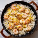 Overhead view of Garlic Butter Shrimp and Rice Skillet garnished with lemon zest and herbs.