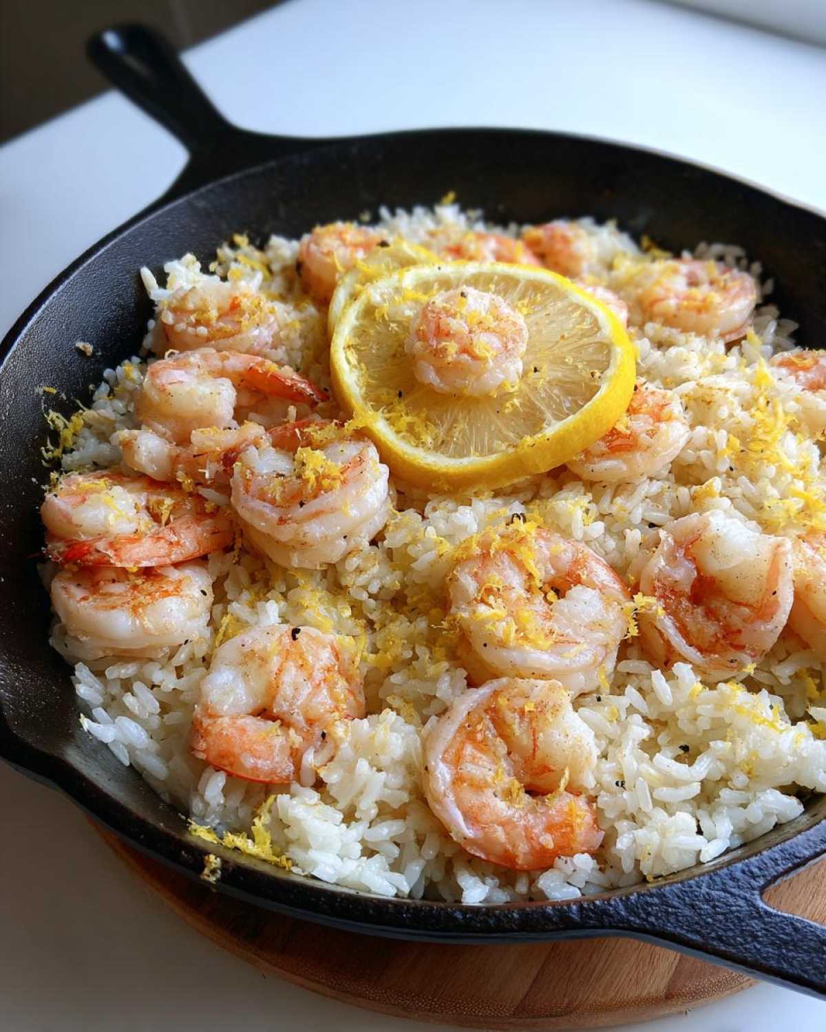Close-up of Garlic Butter Shrimp and Rice Skillet topped with shrimp, lemon zest, and a lemon slice.