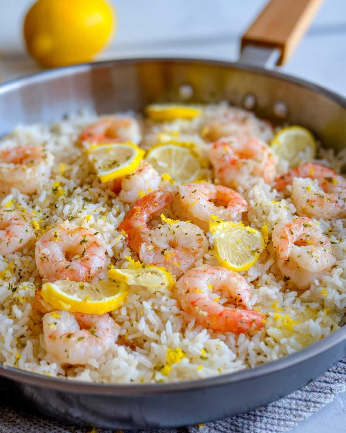Close-up of Garlic Butter Shrimp and Rice Skillet topped with shrimp, lemon slices, and zest.