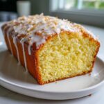 Close-up of a slice of moist Gluten-Free Lemon Coconut Cake topped with white glaze and toasted coconut flakes.