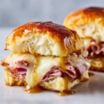 Close-up of a gooey Hawaiian Roll Ham and Cheese Slider dripping with honey mustard glaze and melted Swiss cheese.