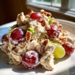A mound of creamy Honey Mustard Chicken Salad with Grapes and pecans served on a white plate.