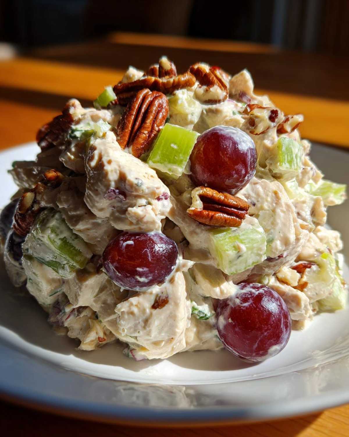 A mound of creamy Honey Mustard Chicken Salad with Grapes, celery, and pecans served on a white plate.