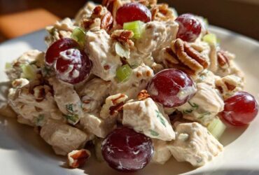 A close-up serving of creamy Honey Mustard Chicken Salad with Grapes, pecans, and celery chunks.