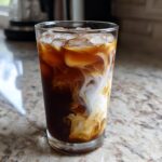 Close-up of an Iced Honey Almond Milk Latte showing rich coffee swirling with creamy almond milk over ice.