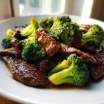 Close-up of tender slices of beef coated in sauce served with bright green broccoli florets: Instant Pot Beef and Broccoli.