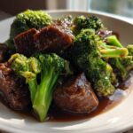 Close-up of tender chunks of beef coated in dark sauce served with bright green broccoli florets in Instant Pot Beef and Broccoli.
